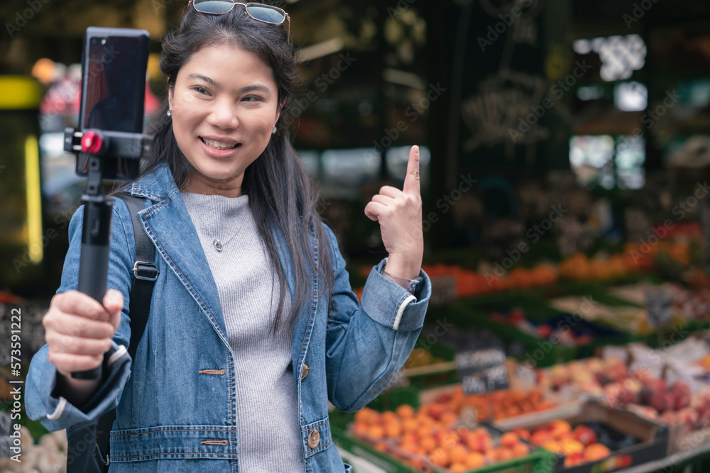 asian female blogger vlogger record vlog streaming video hold phone on selfie stick in open market u