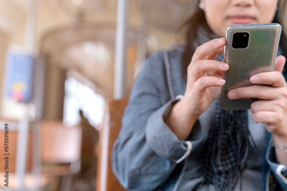 Young and happy asian female woman using smartphone while sitting near the window in the public tran