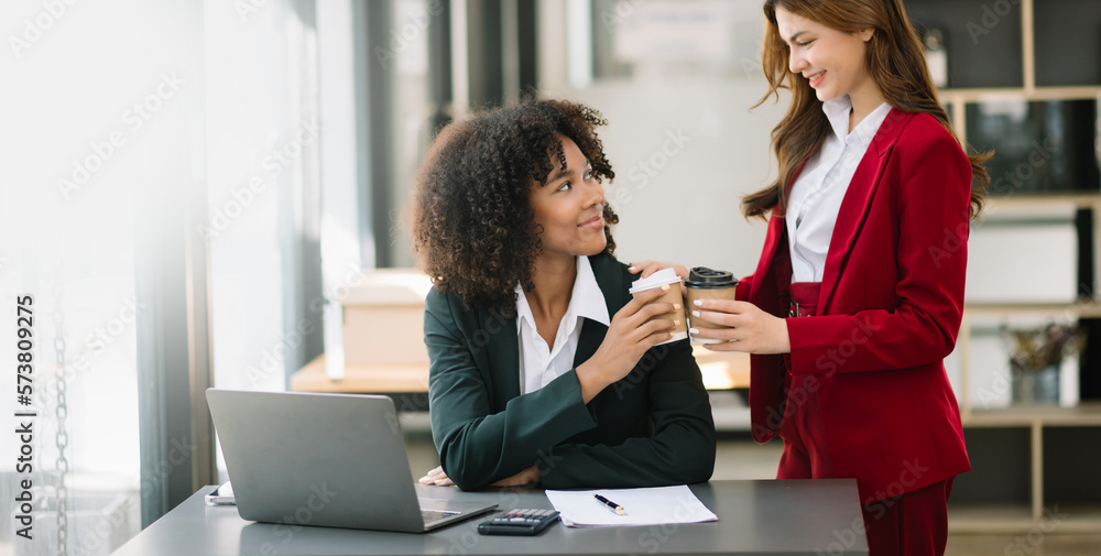 Happy two young business woman holding coffee cup in coworking office.