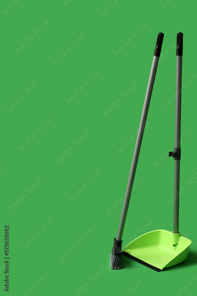 Dustpan with cleaning broom on green background