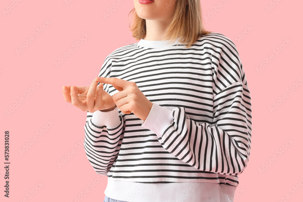 Young woman in striped sweatshirt counting on pink background, closeup