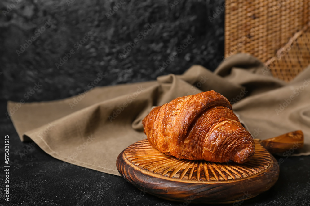 Board with delicious croissant on black table