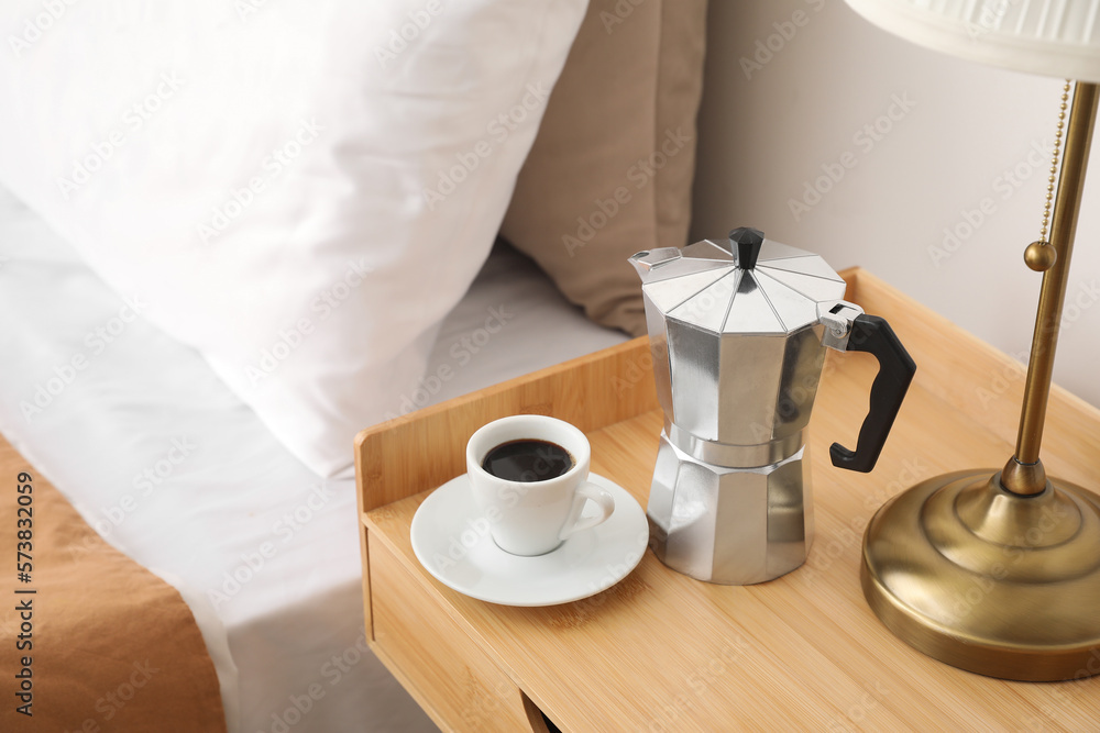 Geyser coffee maker and cup of espresso on nightstand near bed