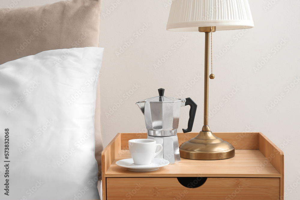 Geyser coffee maker and cup of espresso on nightstand near bed