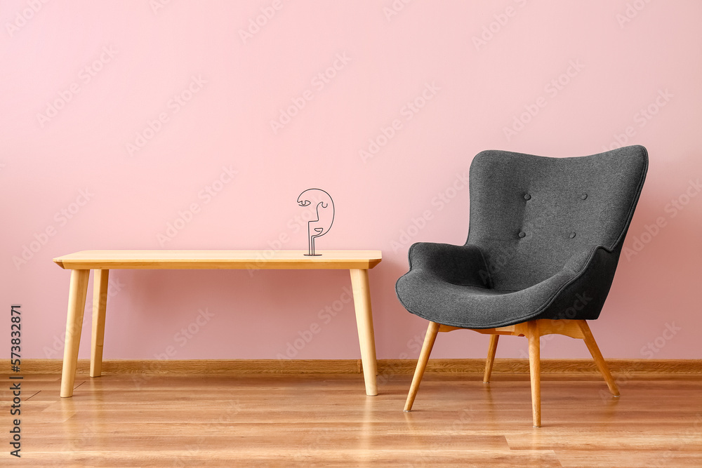 Stylish grey armchair and table near pink wall