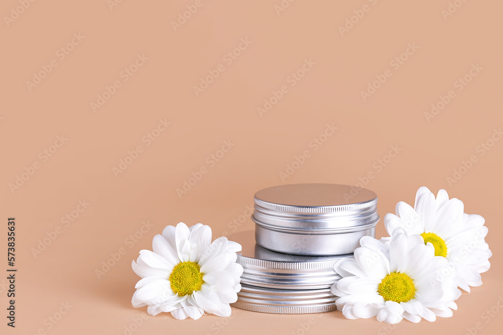 Jars of cosmetic products and chamomile flowers on color background