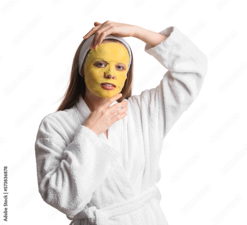 Young woman in bathrobe with turmeric mask on white background