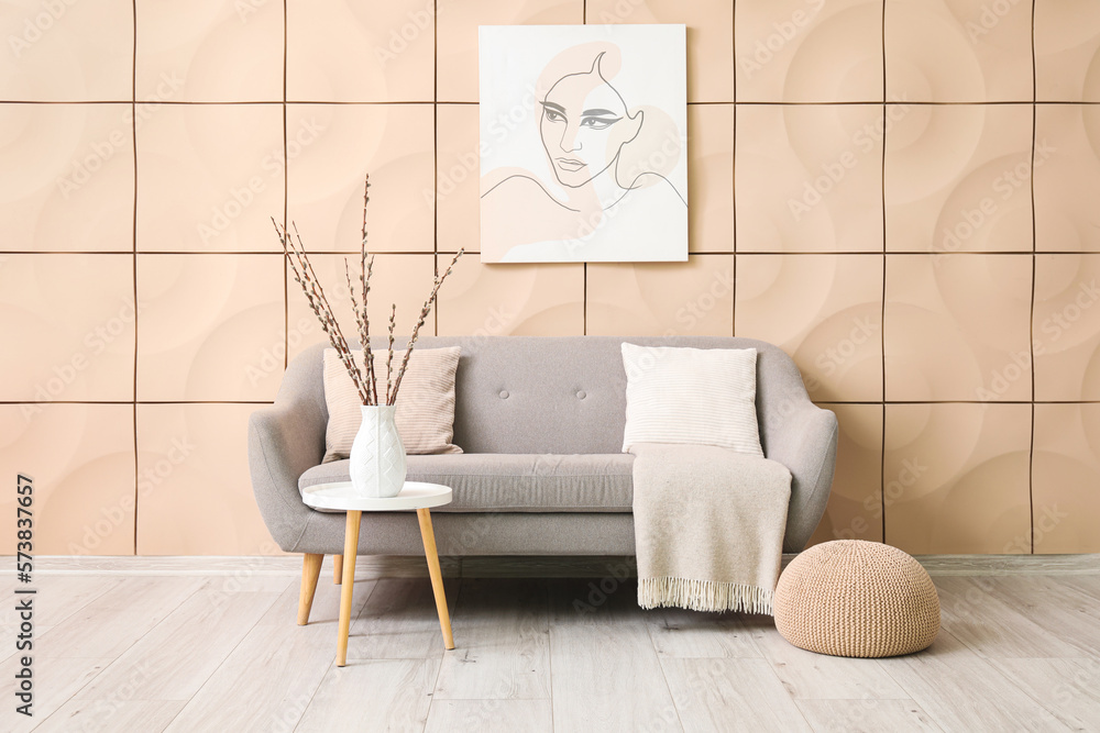 Interior of living room with grey couch and willow branches in vase