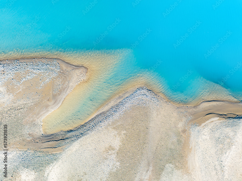 Clear azure water in a mountain lake. The shore with stones. View of the water from a drone. Landsca