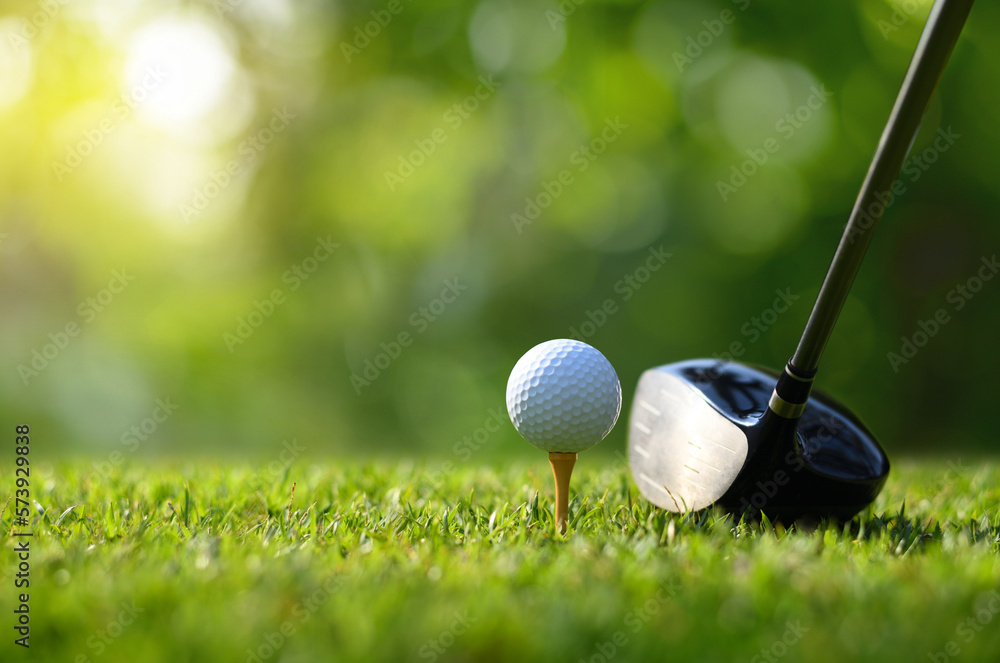 Close-up golf ball on tee with golf drivers at golf course.