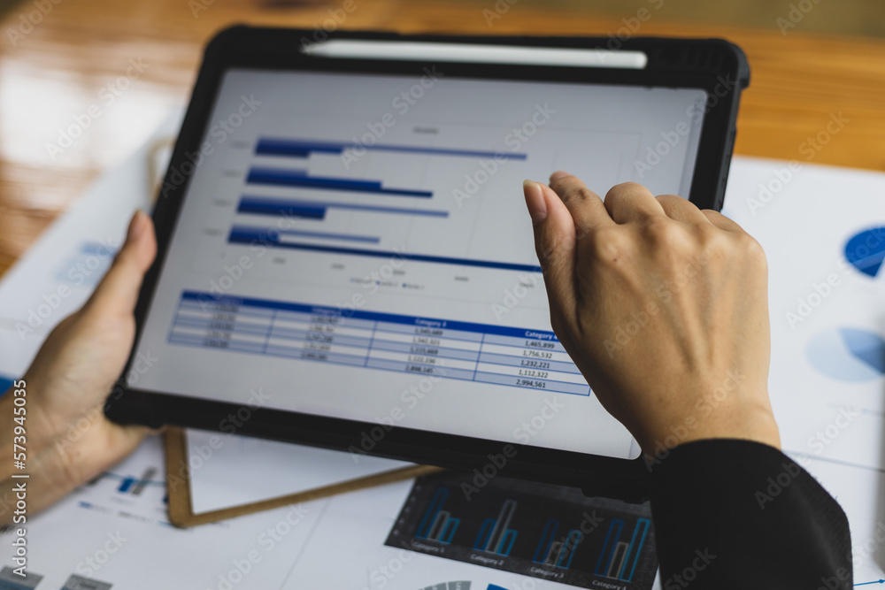 Businesswoman analyzing financial statistics displayed on the tablet screen, working data document g