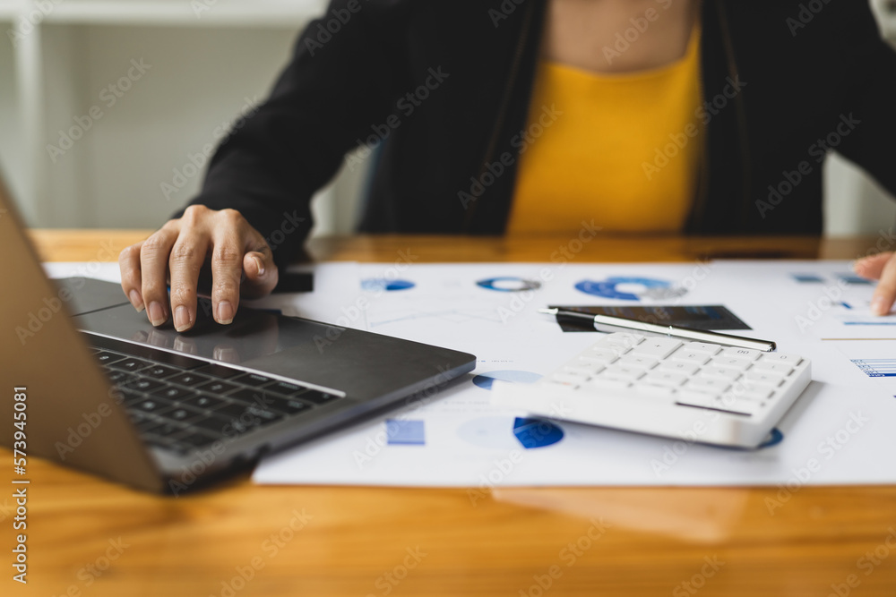 Financial accountant working with laptop and analyzing budget by calculator on desk.