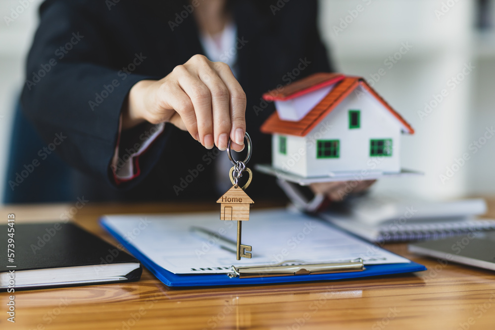 Real estate agent holding keys and model house showing to client, rental house concept.