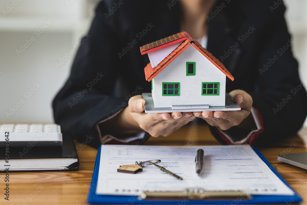 Real estate agent holding keys and model house showing to client, rental house concept.