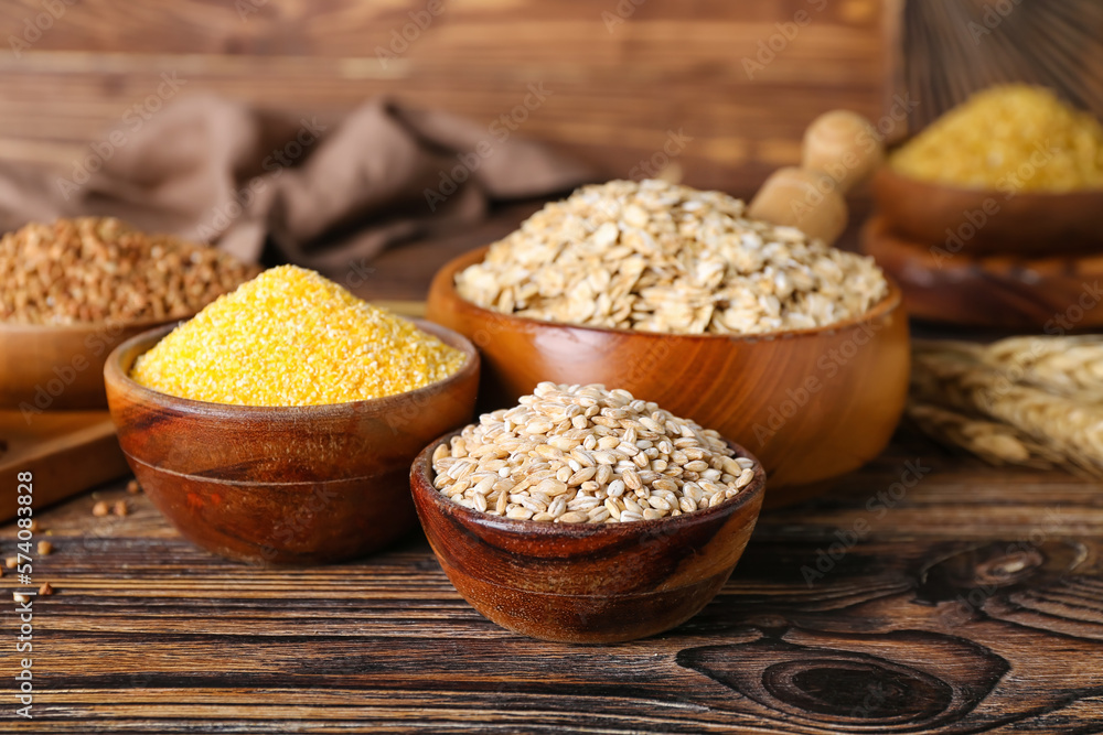 Bowls with different cereals on wooden background