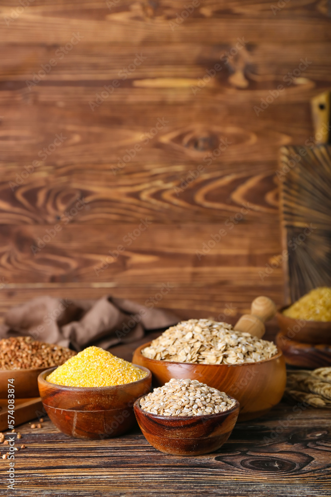 Bowls with different cereals on wooden background