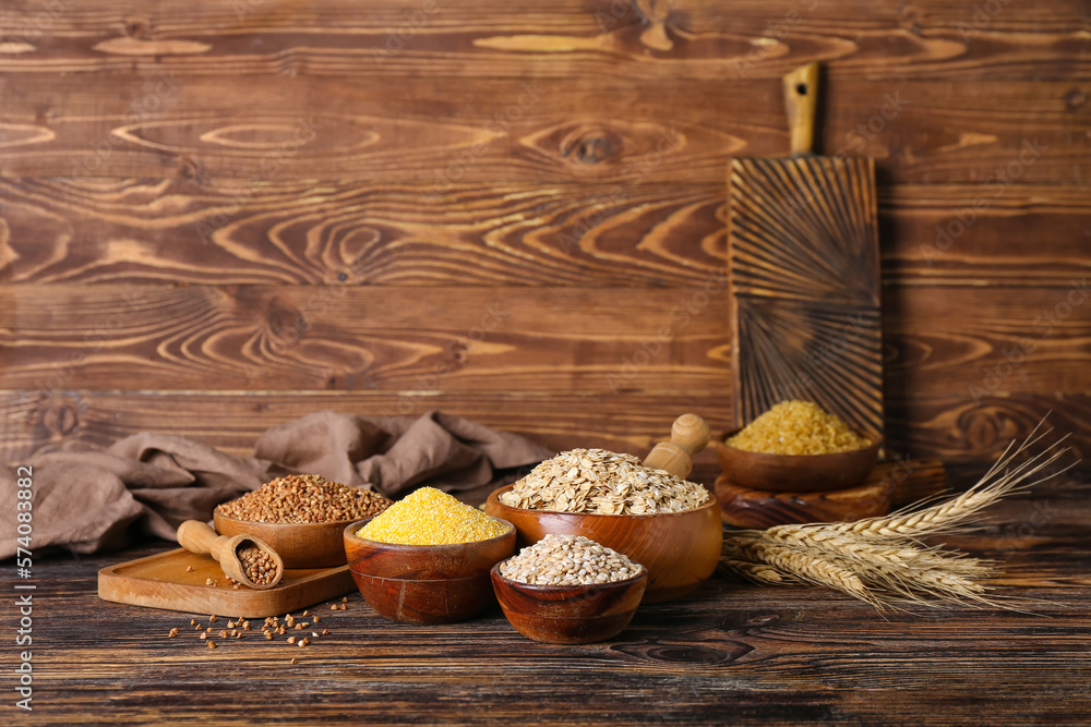 Bowls with different cereals on wooden background