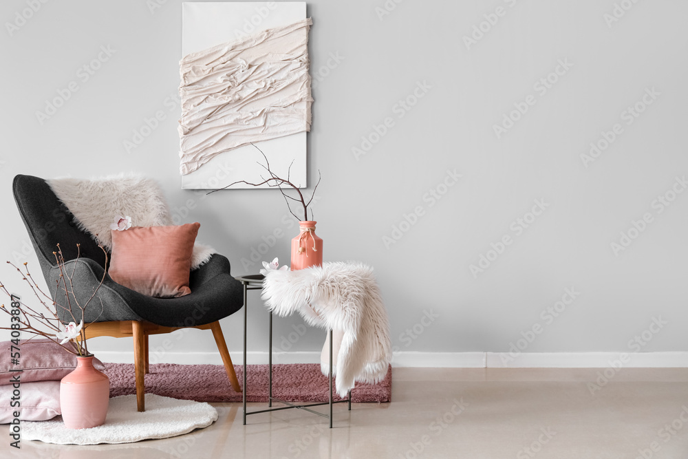 Interior of living room with armchair and tree branches in vases