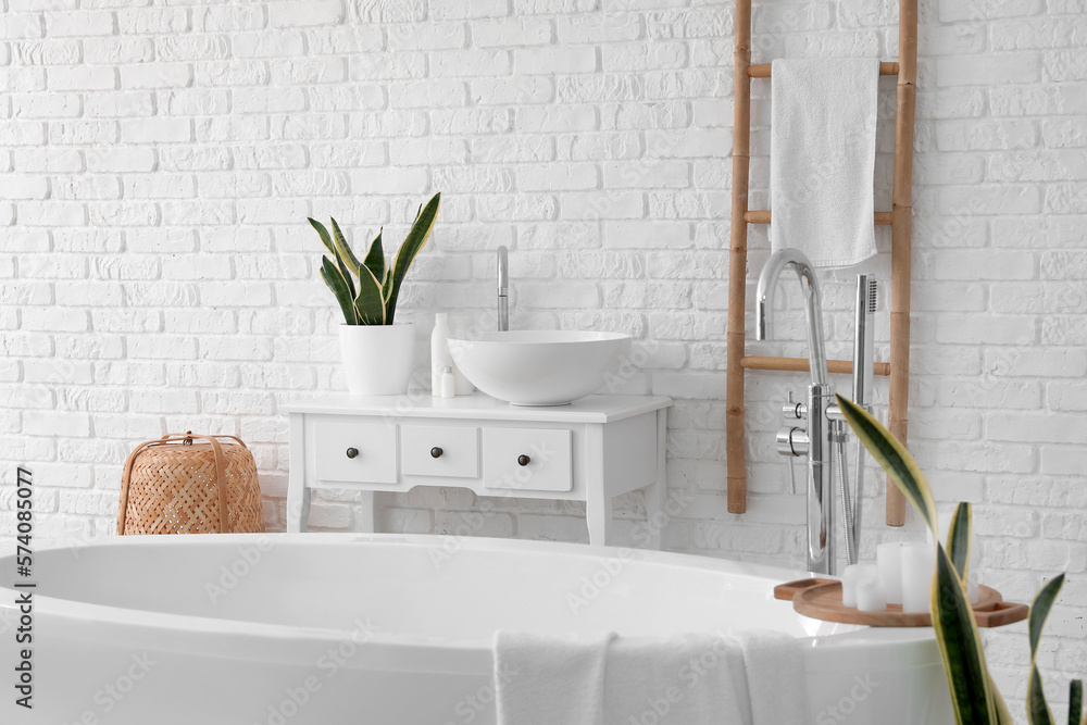 Interior of light bathroom with bathtub, sink and ladder