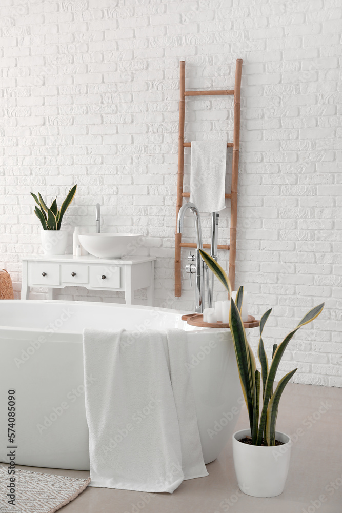 Interior of light bathroom with bathtub, sink and ladder