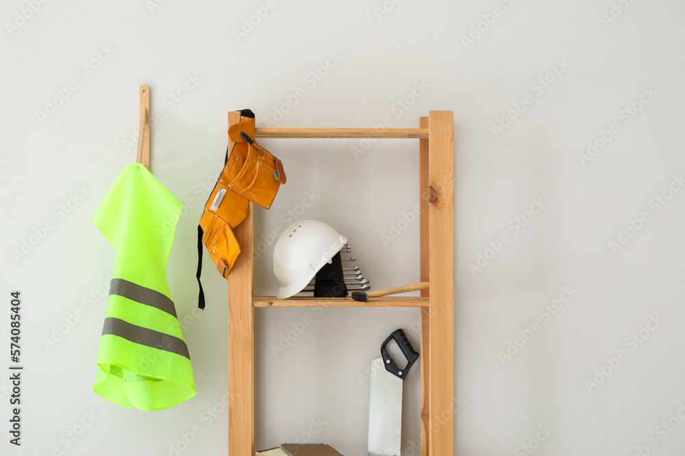 Shelving unit with builders supplies and reflective vest on light wall