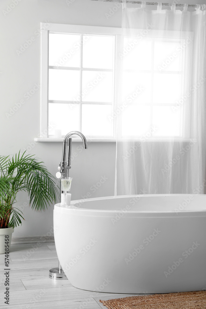 White bathtub in interior of light bathroom