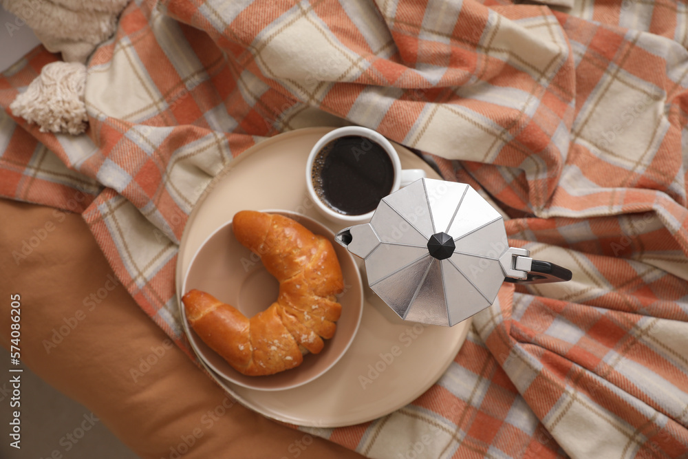 Plate with geyser coffee maker, delicious croissant and cup of espresso on bed