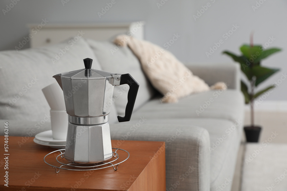 Grid with geyser coffee maker and cups on table in living room