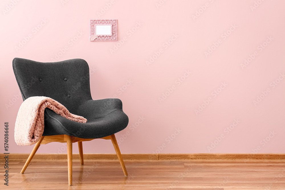 Stylish grey armchair with plaid near pink wall