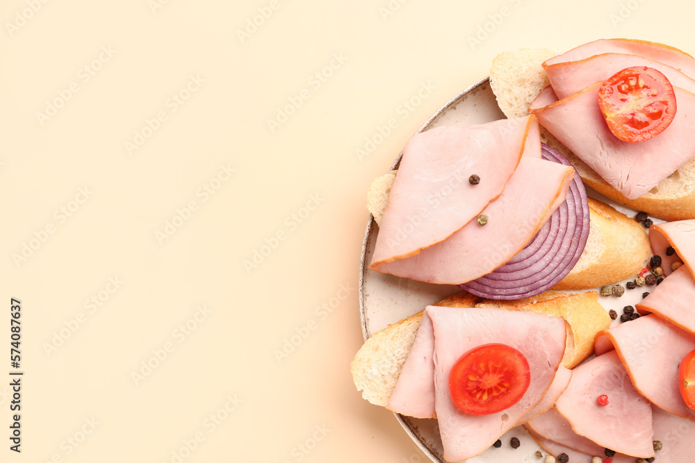 Plate with slices of tasty ham, tomatoes, baguette and onion on beige background