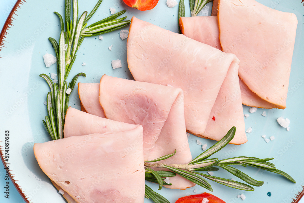 Plate with slices of tasty ham, tomatoes and rosemary on blue background