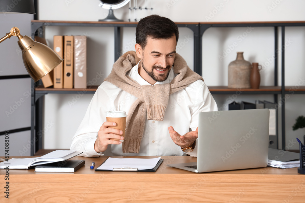 Male tutor with cup of coffee giving online lesson at home