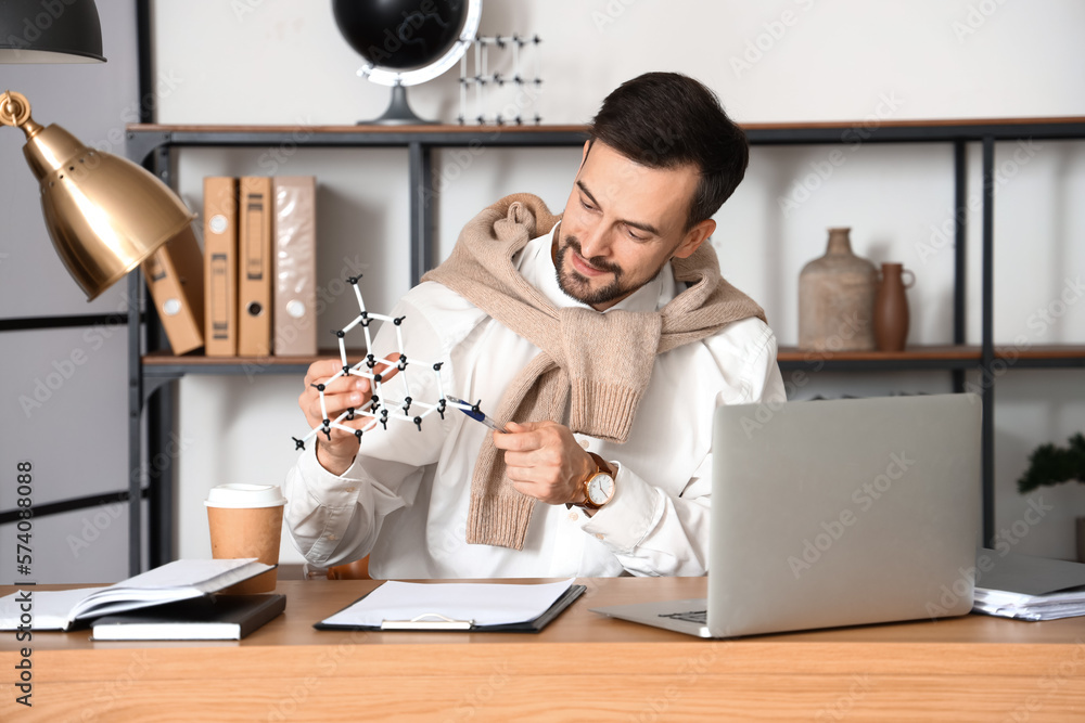 Male tutor with molecular model giving online Physics lesson at home