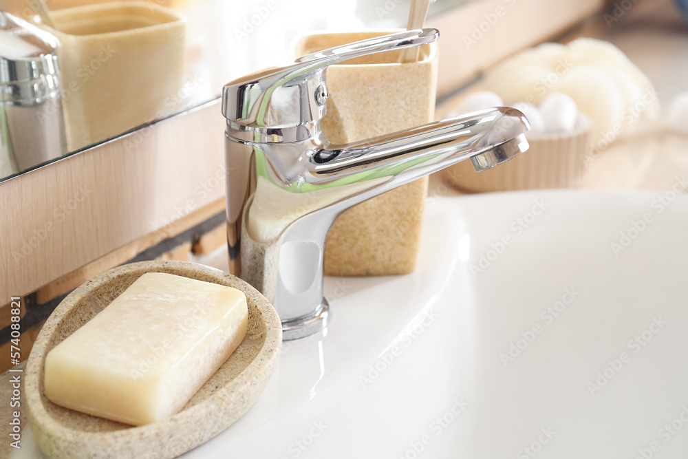 Bowl with soap bar on white ceramic sink, closeup