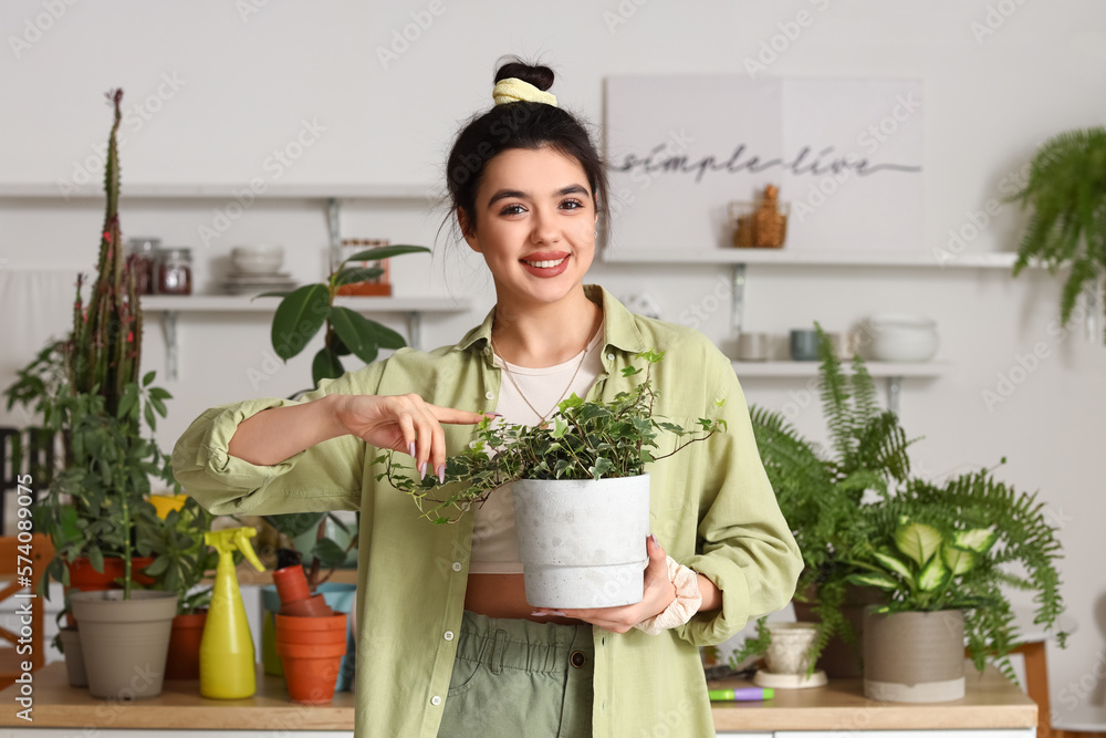 Young woman with green houseplant in kitchen