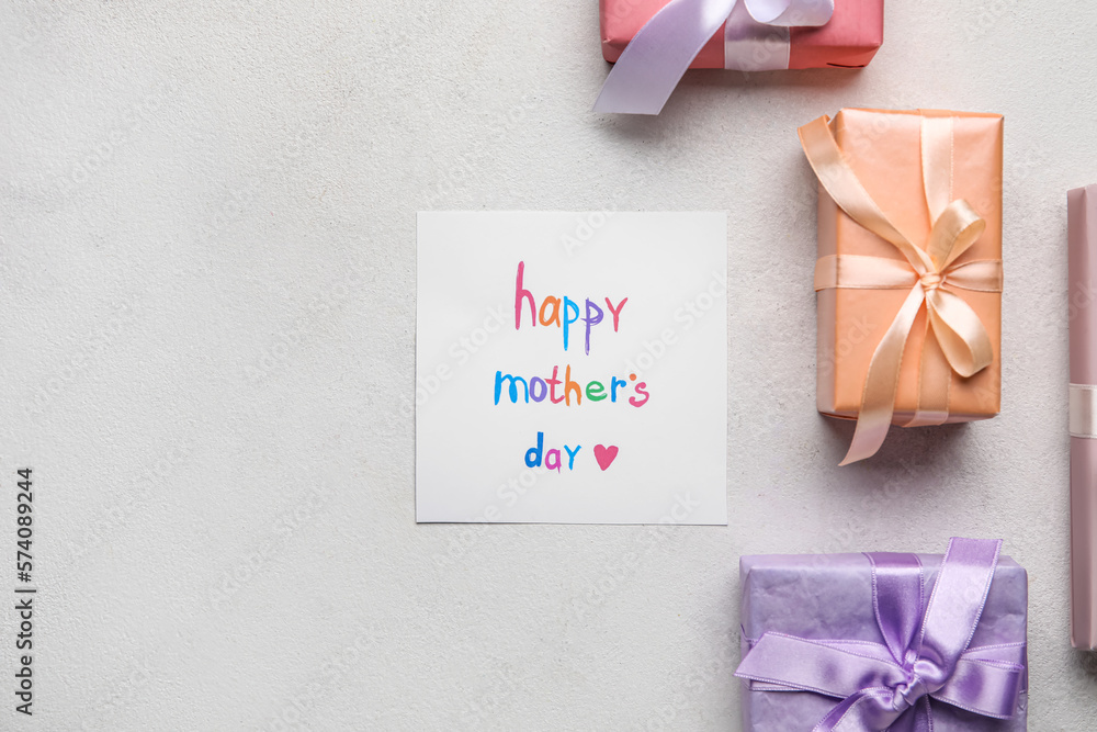 Card with text HAPPY MOTHERS DAY and gift boxes on light background