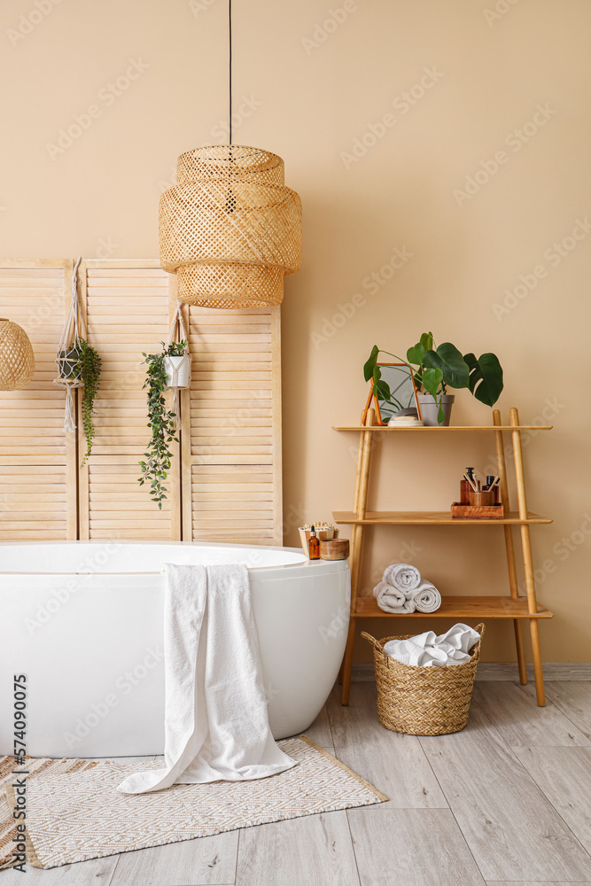 Interior of bathroom with bathtub, houseplants and folding screen