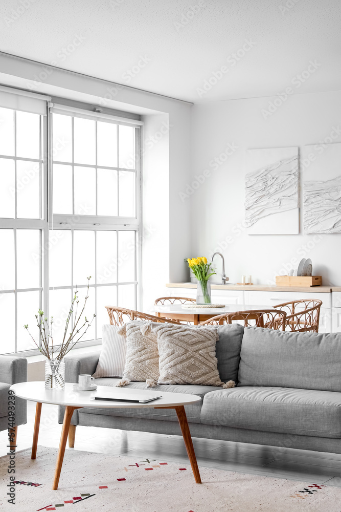 Interior of modern kitchen with grey sofa, dining table and counters