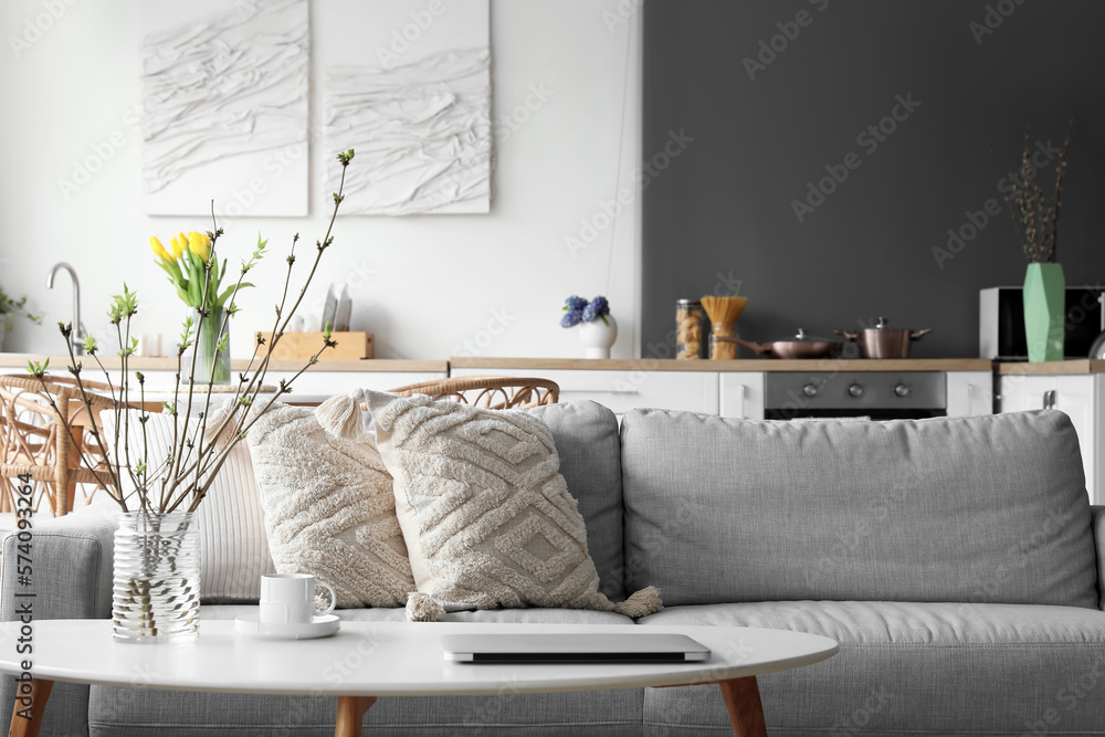 Grey sofa with stylish pillows in kitchen