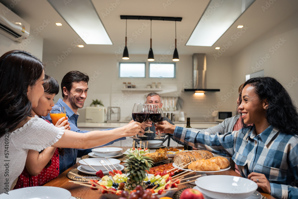 Multi-ethnic big family having dinner, enjoy evening party in house. 