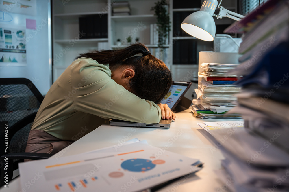 Exhausted Asian young businesswoman overwork late at night in office