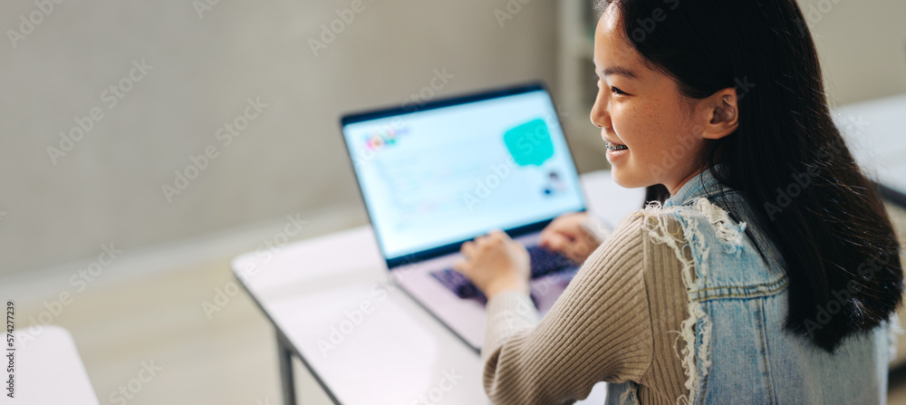 Learning tech skills, young girl sits with a laptop in a coding lesson