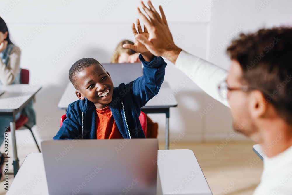 Teacher and student doing a high five in a computer science classroom, celebrating a successful less