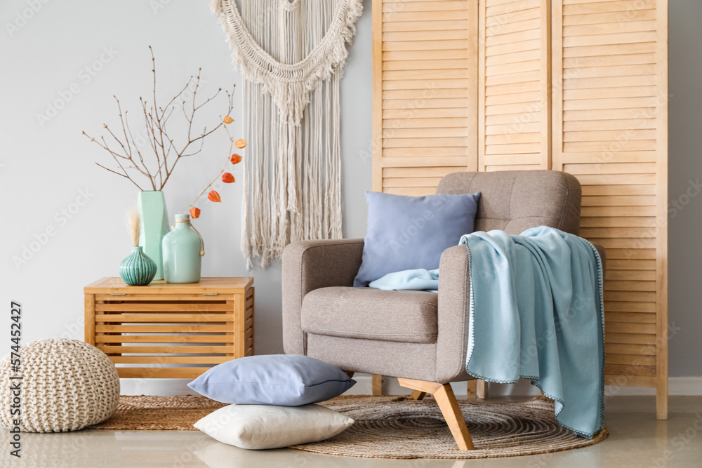 Interior of living room with armchair and tree branches in vases