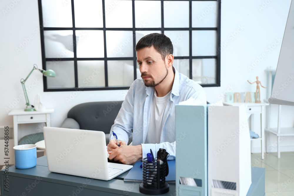 Male tutor with laptop giving online lesson at home