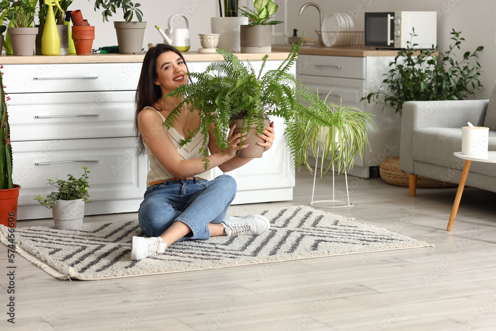 Young woman with green houseplants in kitchen