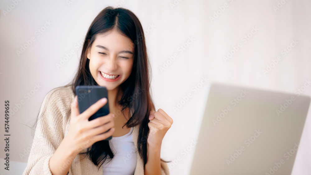 Young asian woman happy working on computer laptop and hand typing chat message on mobile smartphone