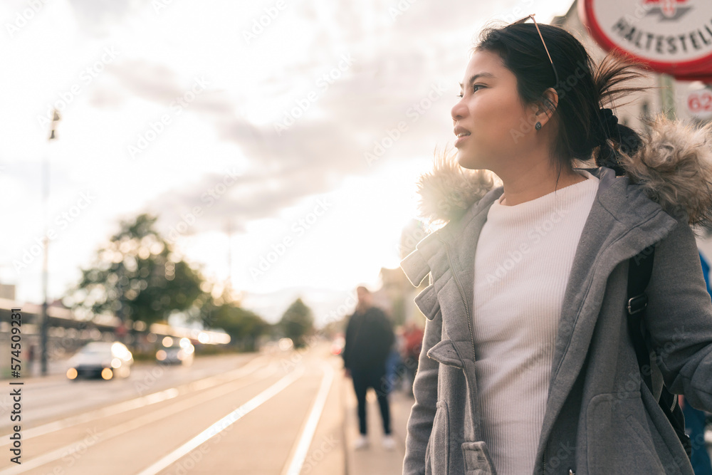 happiness asian carefree woman traveller waiting for city bus tram in Vienna Austria sunset,cheerful