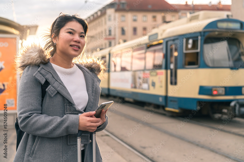 Smiling young asian woman checking schedule table of city traffic online on application using smartp