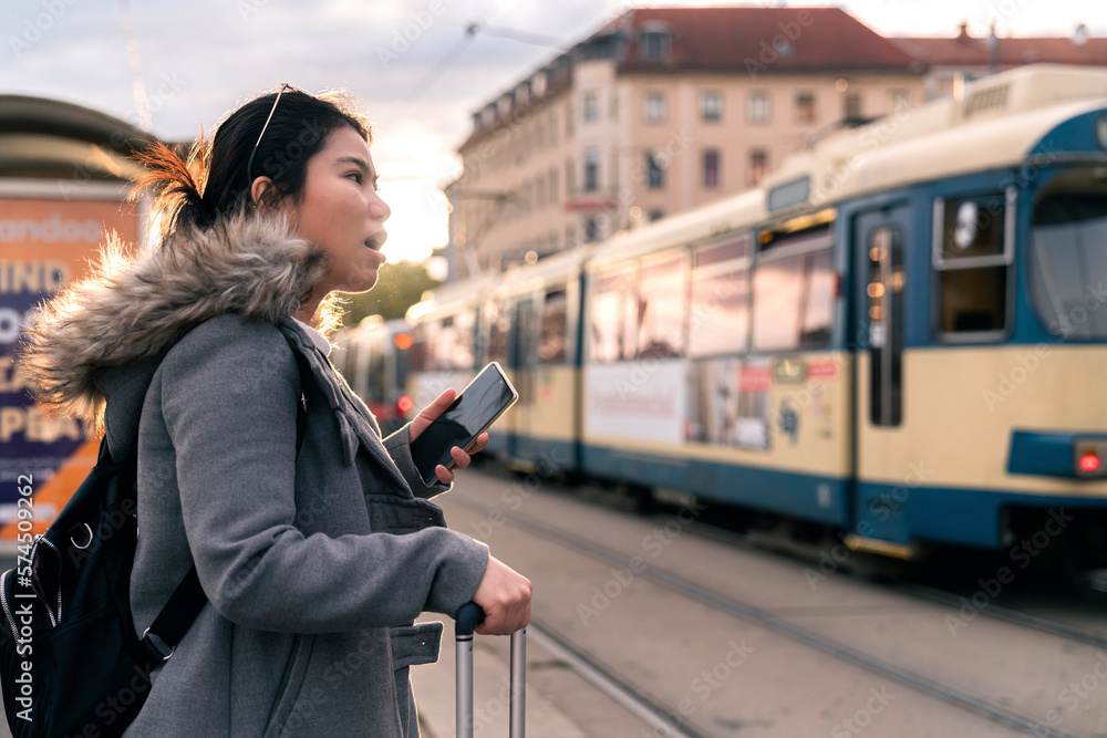 Smiling young asian woman checking schedule table of city traffic online on application using smartp